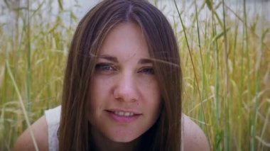 Yakın çekim Kadın gülümsüyor düşük buğday alanında esmer fotoğraf makinesindeki sevinçle görünüyor