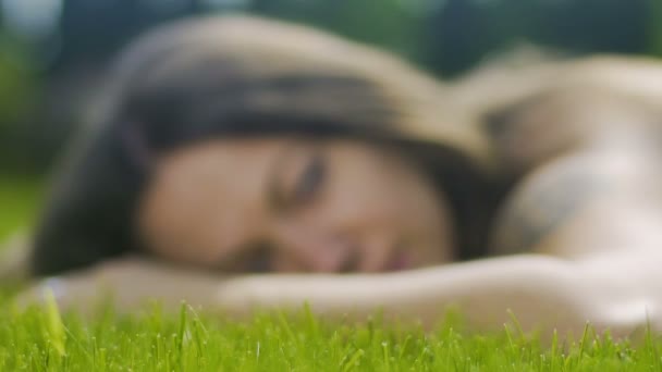 美丽的女性与纹身躺在草地上放松的样子 看无忧无虑的慢 — 图库视频影像
