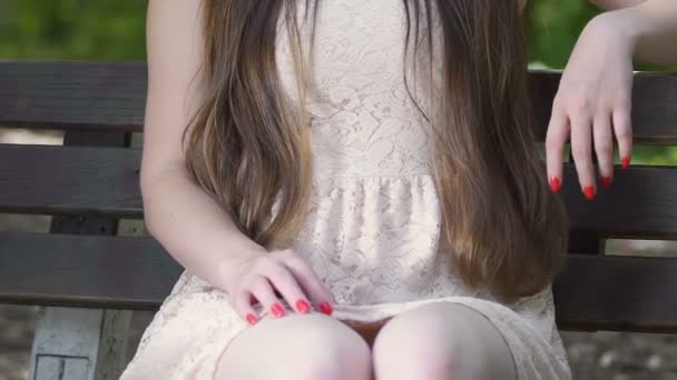 スローモーションのベンチに若い女性は ドレス 魅力的なブルネットのぶりっ子に手を置く — ストック動画