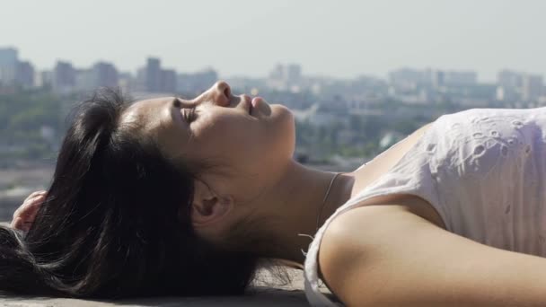 素敵な女性の太陽 背景に都市空行を楽しむ屋上の端の横になっています — ストック動画