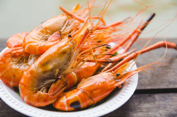 ahşap masa üzerinde beyaz plaka üzerinde ızgara karides