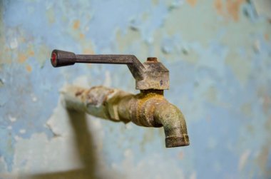 Soluk duvarda eski paslı su musluğu