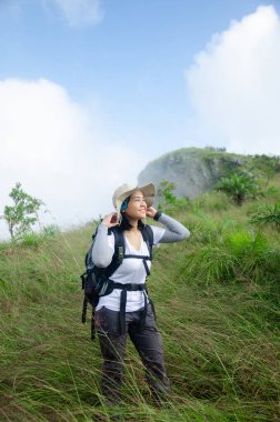 Asyalı genç bir kız dağ yolunda yürüyor gülücükler saçarak dağlarda