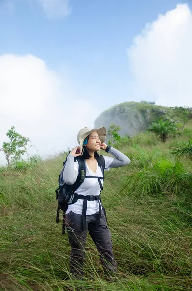 Asyalı genç bir kız dağ yolunda yürüyor gülücükler saçarak dağlarda