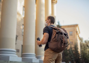 Müzenin arka planında maskeli bir adam kameraya bakıyor.
