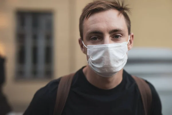 Man in mask against the backdrop of the museum loking at the camera