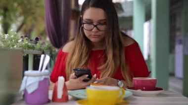 Bir kafedeki masada telefonla konuşan bir kadın.