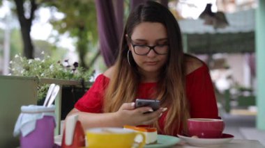 Bir kafedeki masada telefonla konuşan bir kadın.