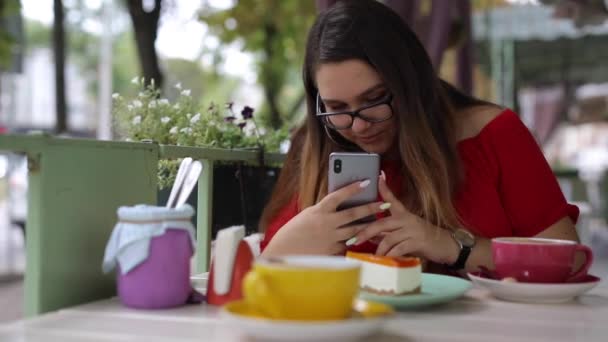 Mulher tira fotos de sobremesas em um café e examina fotos — Vídeo de Stock