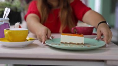Tanınmayan bir kadın cheesecake ikram ediyor ve kahve içiyor.