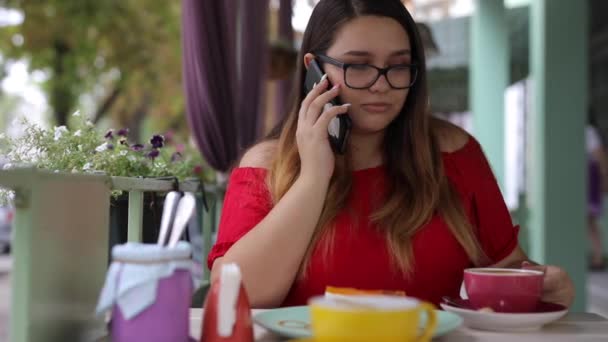 Mulher falando ao telefone em uma mesa em um café — Vídeo de Stock