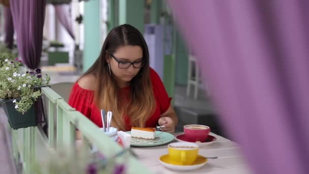 Mooie vrouw eten cheesecake in cafe — Stockvideo