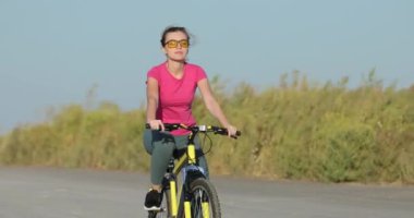 Bisikletçi sarı bisiklet sürüyor, pedal çeviriyor.