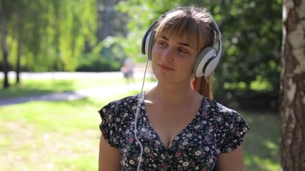 Mujer caminando en el parque con auriculares y escuchando música — Vídeos de Stock