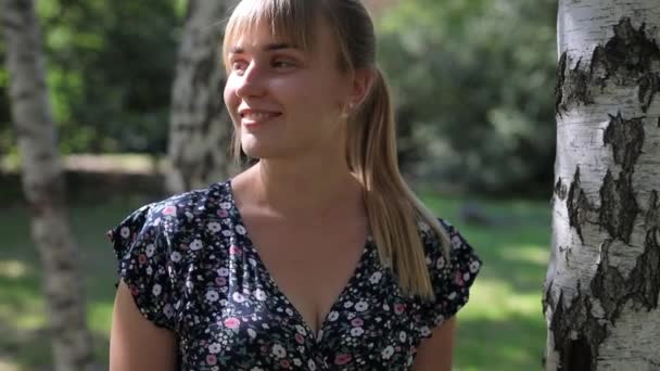 Ευτυχισμένη γυναίκα με ξανθά μαλλιά χαμογελώντας στο πάρκο — Αρχείο Βίντεο