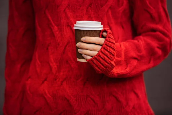 Kırmızı kazaklı tanınmayan kişi elinde bir fincan sıcak içecek tutuyor. — Stok fotoğraf