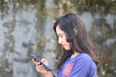Cep telefonu kullanan mutlu bir genç kız. Akıllı telefon ekranında kısa mesajları okuyan genç bir bayan.