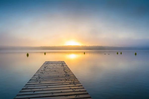 日出时在湖边的码头 背景是薄雾 — 图库照片