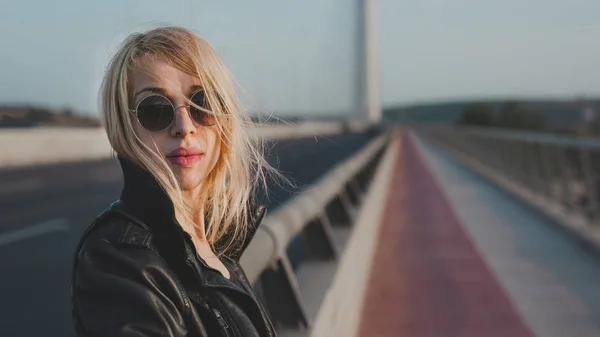 Hipster sevimli kadın seni yaz zevk çekici kızı arıyorlar, güneşli yaz veya bahar günü dışında köprüde duran güneş gözlüklü sarışın genç kadın.
