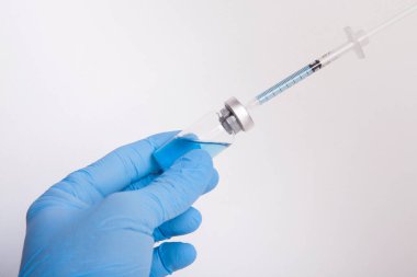 Doktor elinde ilaç şişesi ve şırınga tutuyor..