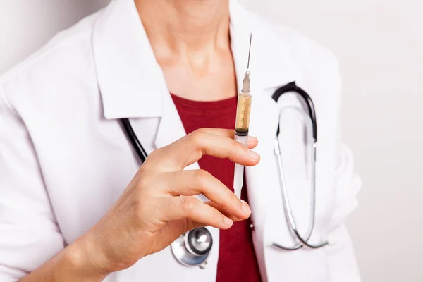 Doktor elinde bir şırınga tutuyor..