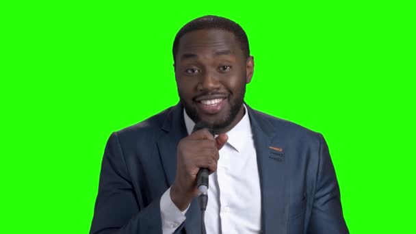 Hombre sonriente con micrófono en pantalla verde . — Vídeos de Stock