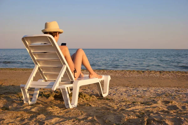 Vista posterior mujer joven usando smartphone en la costa de la playa . —  Fotos de Stock