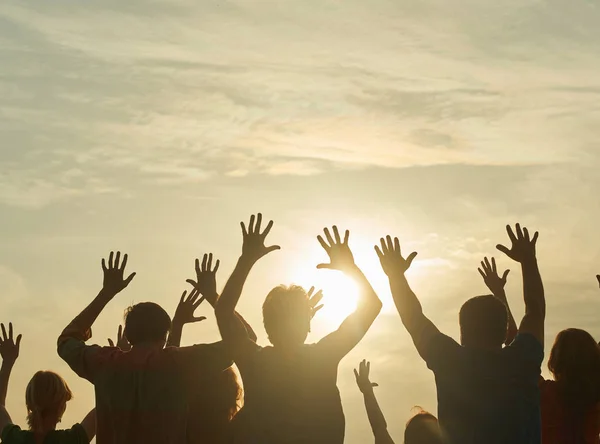 Gente con las manos en alto al amanecer . — Foto de Stock