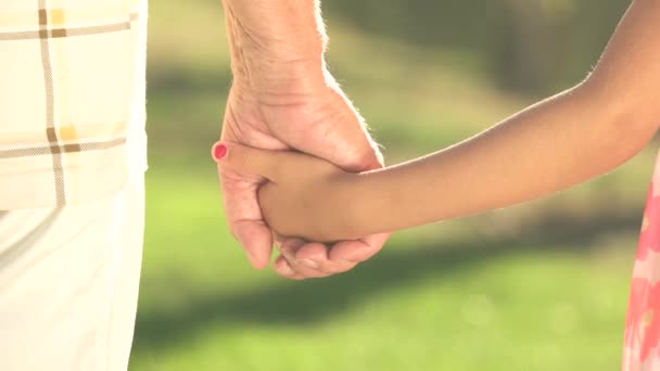 Alter Mann und Kind halten Händchen.