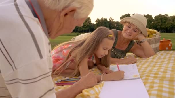 Schoolchild dessine avec des crayons de couleur à l'extérieur . — Video