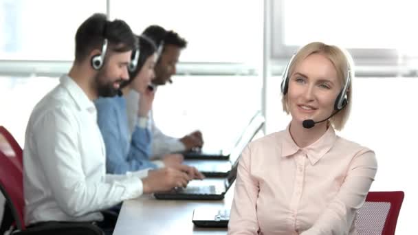 Vrolijke blonde dame in callcenter raadpleging van een client. — Stockvideo
