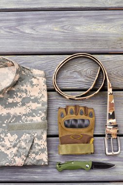 Bükülmüş kemer, eldiven, cep bıçak ve kamuflaj ceketi.