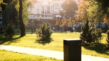 Binalar ve ağaçlar ile kalabalık şehir parkı.