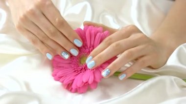 Pembe gerbera ve Genç manikürlü eller.