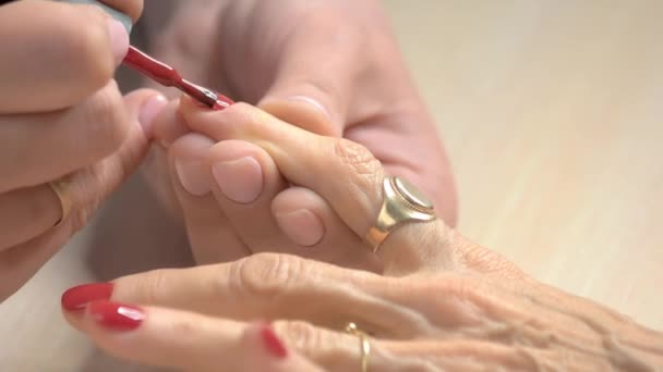 Especialista em unhas aplicando verniz vermelho . — Vídeo de Stock