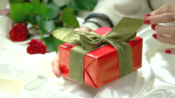 Руки касаются банта на подарочной коробке . — стоковое видео