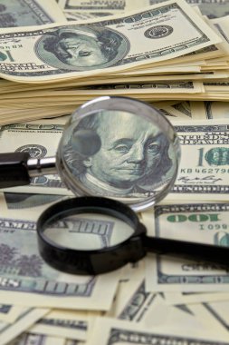 Yüz dolar faturaları büyüteçler ile yığını.