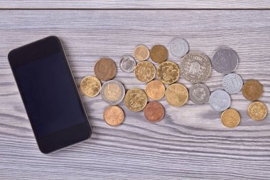Smartphone ve sikkeler üzerinde ahşap.