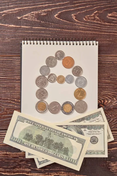 Coins and dollars with notepad. — Stock Photo, Image