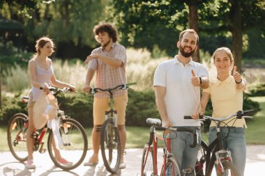 Neşeli çift başparmak yukarıya el hareketi Bisiklet.