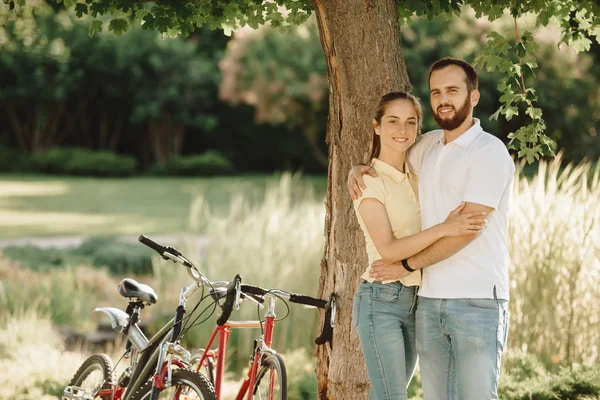 Jovem casal de ciclistas está abraçando ao ar livre . — Fotografia de Stock