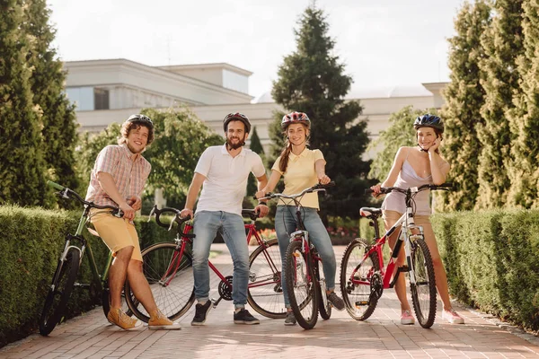 Group of smiling friends with bikes outdoors.