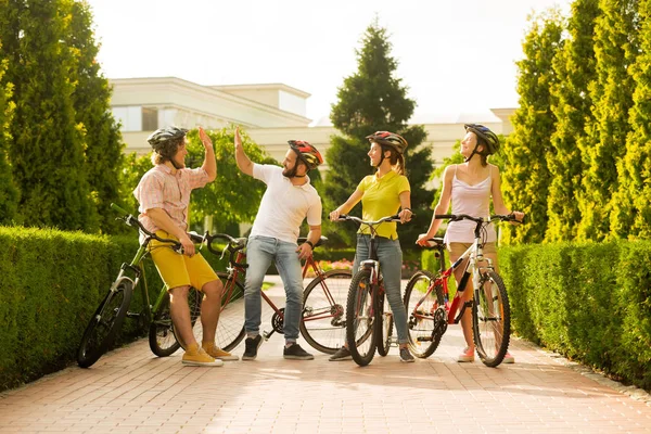 Sporty company of friends with bicycles outdoors.