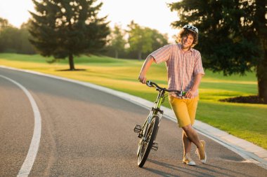 Gülümseyen adam ülke yolda bisiklet ile dinlenme.