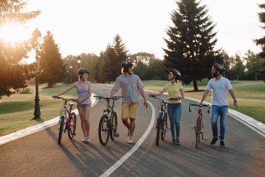 Grup neşeli bisikletçiler Bisiklet aşağı belgili tanımlık yol ile yürüyüş.