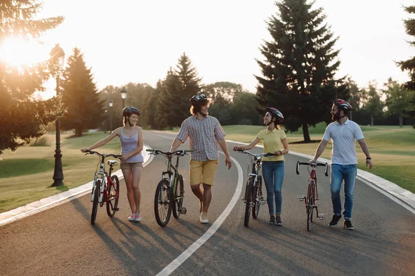 Groupe de cyclistes joyeux marchant avec des vélos sur la route . — Photo