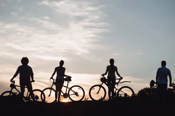 Quatre jeunes cyclistes au beau coucher du soleil . — Photo