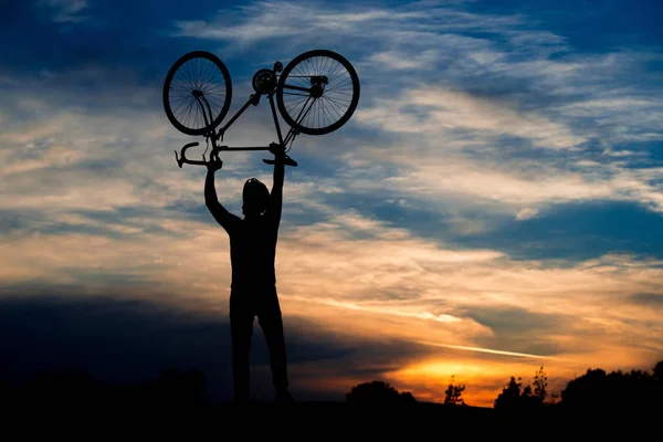 Silhouette du cycliste tenant le vélo au-dessus de la tête . — Photo