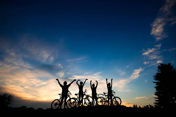 Amis avec des vélos au coucher du soleil fond . — Photo