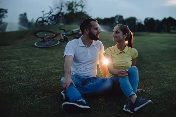 Paret sitter på gräset i parken kväll. — Stockfoto